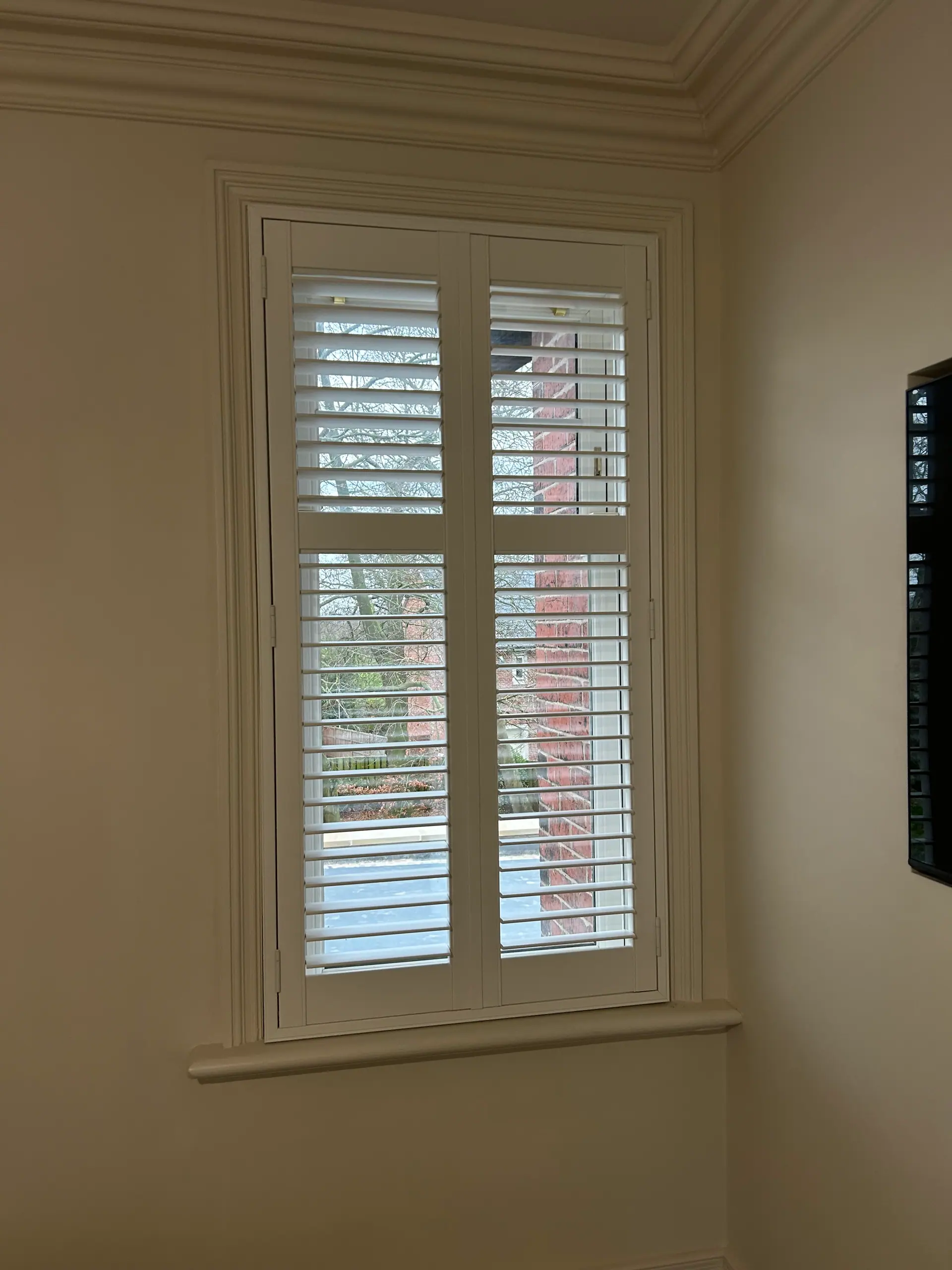 White tier-on-tier shutters fitted to a tall sash window