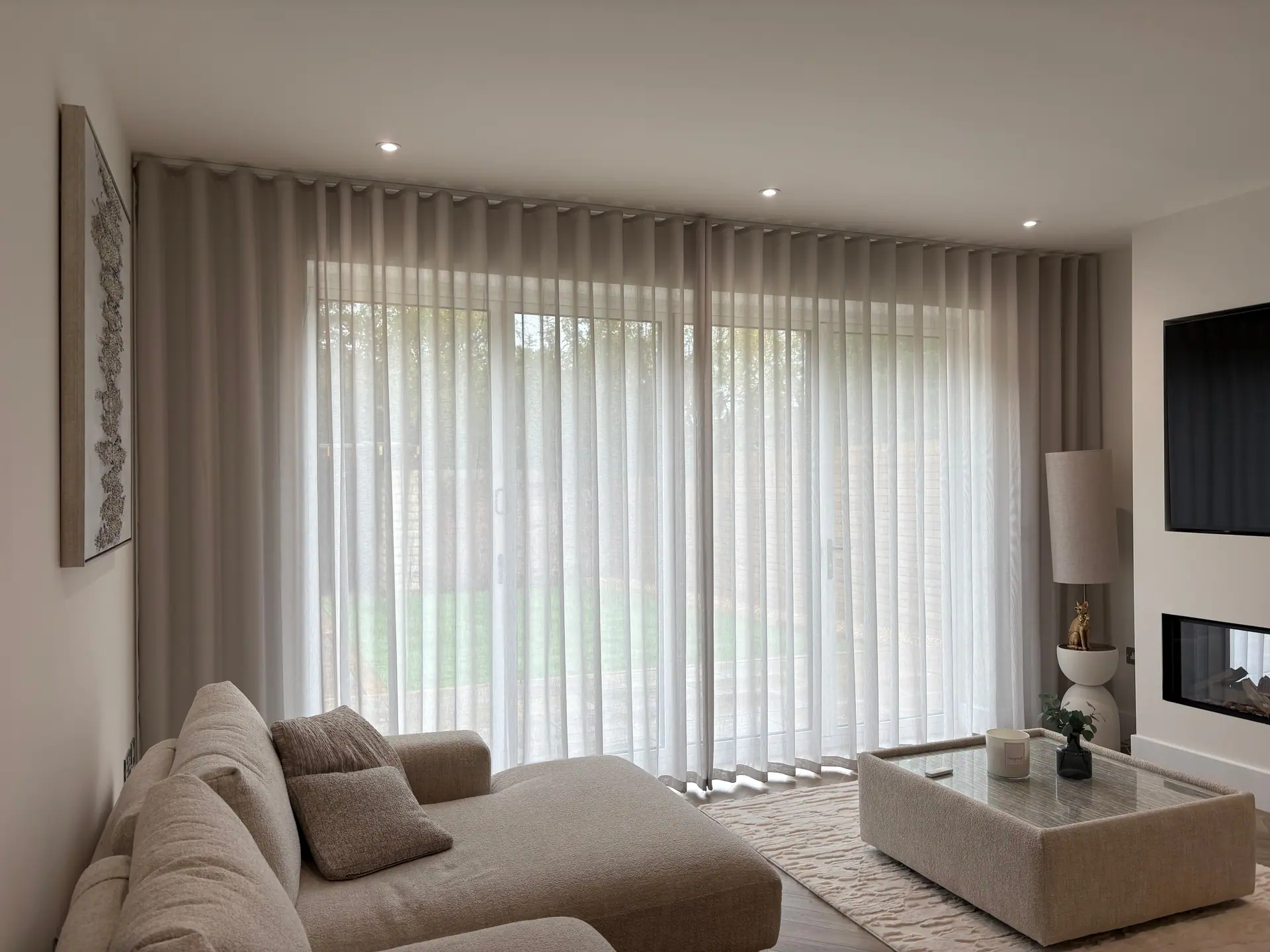 Sheer wave curtains across floor-to-ceiling sliding doors in a neutral living room